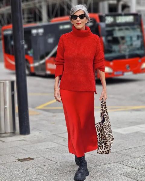 Женщина в красной атласной юбке, черных ботинках и свитере